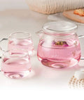 Sleek Heat Resistant Glass Teapot For Cold Brew And Hot Tea with cups featuring pink liquid and floral details.