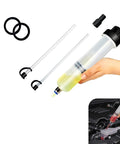 Hand holding Power Steering Fluid Extractor And Refill Pump Kit, 200cc Manual Suction And Injection Tool With Hoses near a car engine