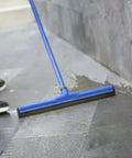 Person using blue squeegee on natural stone floor applying Water Based Stone Enhancer And Sealant For Marble Granite Limestone.