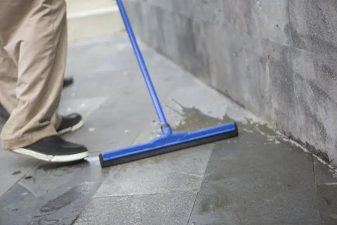 Person using blue squeegee on natural stone floor applying Water Based Stone Enhancer And Sealant For Marble Granite Limestone.