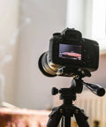 Camera mounted on a tripod, focused on a table setting, demonstrating the use of a mounting grip knob for stability.