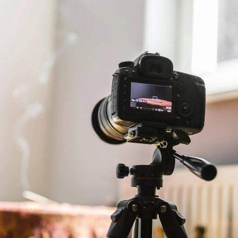 Camera mounted on a tripod, focused on a table setting, demonstrating the use of a mounting grip knob for stability.