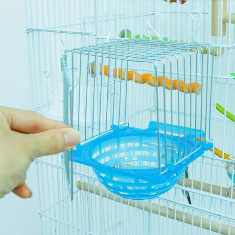 4 Pack Slick Bird Hatching Nest Bowls Featuring A Secure Barbed Wire Partition installed in a birdcage with a hand holding it.