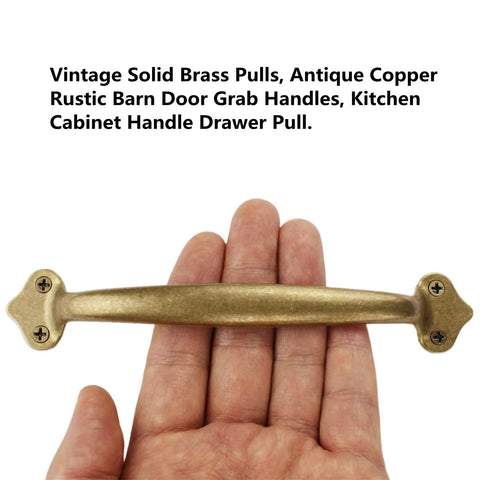 Hand holding vintage solid brass pull in antique copper finish, rustic barn door handle for cabinets and drawers, 6.5 inch length.
