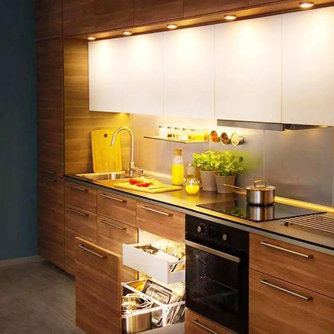 Modern kitchen with under-cabinet lighting, showcasing sleek wood cabinetry and stainless steel appliances in a cozy setting.