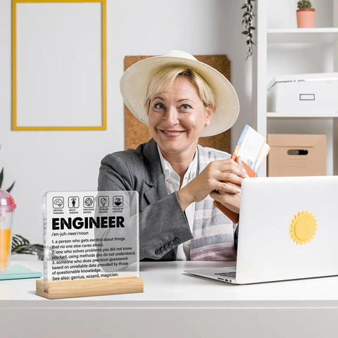 Engineer Gift For Men Dope Engineering Desk Decor Engineer Definition Clear Acrylic Sign For Home Office Decor 4 By 4 Inch Ideal Birthday Gift Idea Gift For Engineers on office desk with smiling woman, laptop, and decor items in the background
