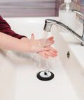 Rubber Bathtub Drain Plug with Stainless Steel Easy Pull-Out Stopper in a sink with water flowing and a child's hands.