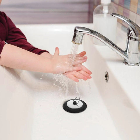 Rubber Bathtub Drain Plug with Stainless Steel Easy Pull-Out Stopper in a sink with water flowing and a child's hands.