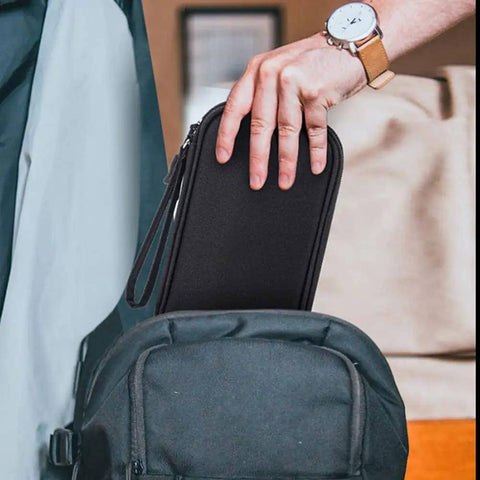 Hand placing Heavy Duty Workhorse Tech Organizer Pouch into a black backpack for cord storage.