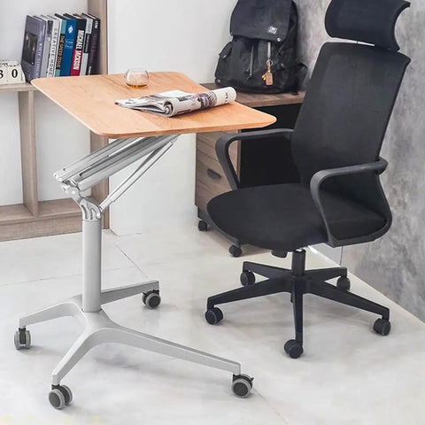 Hella Stable Mobile Standing Desk Featuring Instant Gas Spring Lift And Smooth Glide Rollers For A Total Game Changer Home Office Upgrade Or Flexible Workspace Setup In Clean Black next to a black office chair.