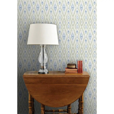 Next Level Ikat Stripes Faux Vinyl Wallpaper With Durable Subtle Leather Grain Finish Engineered For Bustling Commercial Spaces And Custom Sized To Fit Your Walls Built Tough For Years, featuring green and blue ikat designs behind a decorative lamp and wooden table.