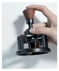Heavy Duty 58 Millimeter Espresso Portafilter Needle Distributor With Built In Magnet, hand holding tool for coffee ground preparation.