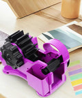 Heavy Duty Semi Automatic Packing Tape Dispenser Smooth Operator Design With Nifty Dual Cutting Station showing purple device on crafting table.