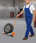 Person using Beefy Heavy Duty Tire Dolly For Garage And Auto Repair Wheel Tire Moving Cart for transferring heavy wheels safely.