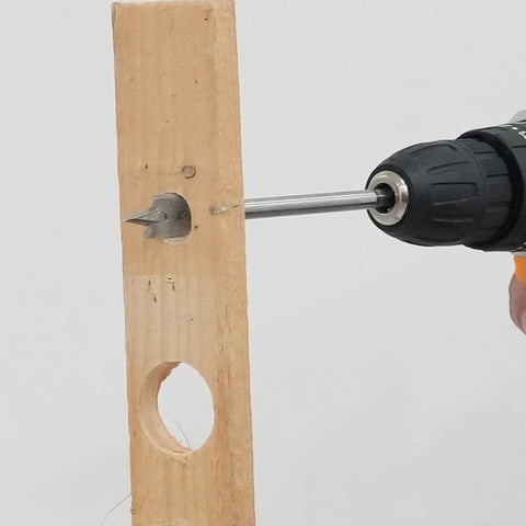 Close-up of a drill with a spade bit cutting through wood, from the 13 Piece Spade Drill Bit Set For Woodworking, Paddle Bits With Quick Change Shank, Carbon Steel Heat Treated For Durability, Sizes 1/4 To 1-1/2 Inch, Includes Nylon Storage Pouch, Built Tough For Pro Level Cuts GMTOOLS.