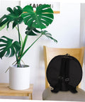 Heavy Duty Adjustable Drum Backpack With Massive Capacity Oxford Fabric Waterproof Gig Bag on a chair next to a plant.