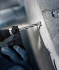 Close-up of an SDS-Plus rotary hammer drill bit drilling into a concrete wall; Rannb 4-piece set (6, 8, 10, 12 mm)