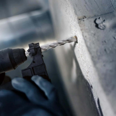 Close-up of an SDS-Plus rotary hammer drill bit drilling into a concrete wall; Rannb 4-piece set (6, 8, 10, 12 mm)