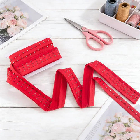 Rock Solid Three Inch 3 Row Hook And Eye Bra Extender Tape In Vibrant Red laid flat with scissors and sewing supplies, crafted from heavy duty polyester.
