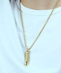 Gold Bullet Pendant Necklace With Engraved Cross And Bible Charm Premium Stainless Steel Unisex Jewelry worn on white shirt.