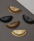 5 decorative drawer handle shells in gold and black finishes, showcasing detailed textures and antique style.