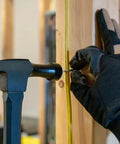 18 Oz Electrician Hammer With Extended Neck For Tight Spaces, Romex Staple Remover, in use with gloved hand in construction setup