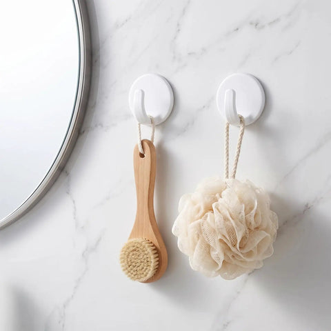 Eight Piece White Peel And Stick Wall Hooks Offer A Super Strong Hold That Skips The Drilling Headaches While Making Everyday Organizing Easy Peasy And Totally Damage Free For Any Room, holding a wooden brush and a loofah.