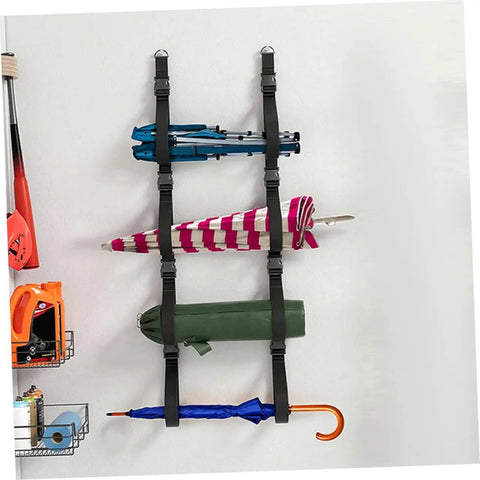 Heavy Duty Adjustable Wall Storage Straps With Badass Rugged Buckles Perfect For Camping Chairs Yoga Mats And Tents securely holding umbrellas and gear on a wall.
