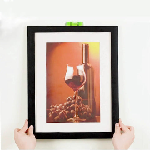 Hands hanging a picture frame using Heavy Duty Picture Hanging Strips 24 Pairs 48 Strips Removable Hook And Loop Mounting Tape