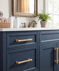 Top Tier Brushed Brass Cabinet Pulls 10 Pack Featuring 96MM Hole Spacing on a navy bathroom vanity with a marble top.