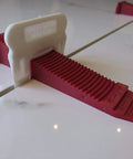 One Eighth Inch T Lock Tile Leveling Kit With 300 Spacers And 100 Wedges In Handy Bucket For Ultra Precise Lippage Control And Clean Grout Lines Pro Grade For Pros And DIY Tile Installers showing a red wedge securing tile