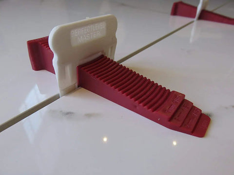 One Eighth Inch T Lock Tile Leveling Kit With 300 Spacers And 100 Wedges In Handy Bucket For Ultra Precise Lippage Control And Clean Grout Lines Pro Grade For Pros And DIY Tile Installers showing a red wedge securing tile