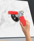 Side view of a red-handled 4-inch pneumatic wet stone polisher pressed against a marble slab.