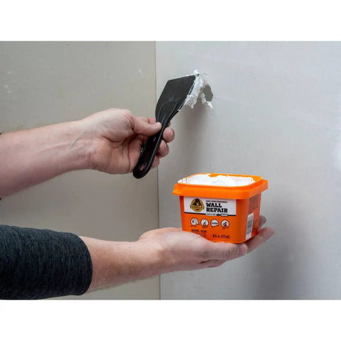 Person applying Heavy Duty Wall Repair Spackling Plus Primer 16 Oz White Tub Patch Cracks Holes And Uneven Ceilings With Smooth Finish