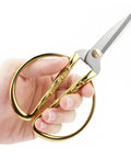 Hand holding gold-handled scissors from Retro Dandelion All In One Sewing Kit Box Basket Wooden Handcrafted Home Repair Tool Kit For Beginners.