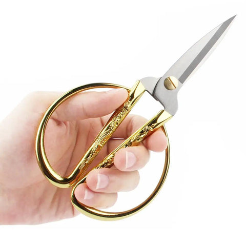 Hand holding gold-handled scissors from Retro Dandelion All In One Sewing Kit Box Basket Wooden Handcrafted Home Repair Tool Kit For Beginners.