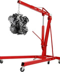 Shop Essential Two Ton Hydraulic Engine Hoist With Six Swivel Rollers And Quick Fold Frame lifting an engine block in a garage.