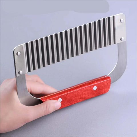 Side view of handheld stainless steel crinkle cutter with red wooden handle; ridged blade for slicing vegetables.