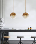 Modern Globe Pendant Light With Gradient Glass Shade, Gold Finish, 1 Light, Adjustable Height Chandelier For Dining Room, Kitchen, And Bedroom, E26 Base, Dope Mid Century Vibe, Premium Glass And Metal Fixture hanging above a dining table in a stylish room