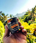 Hand holding a Yaucono coffee cup with nature and mountains in the background, vibrant and sunny setting.