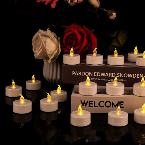 12 Pack Flameless Tea Lights LED Candles With Realistic Flicker And Cozy Warm Yellow Glow For Halloween Decor Pumpkin Centerpieces Wedding Garden Party Home Decor Battery Included Long Lasting Ambience, displayed on books with roses.