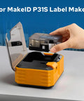 For MakeID P31S Label Maker, showcasing a hand inserting a label cartridge into the device on a work surface.