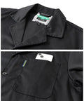Durable Mechanic Lab Coat For Men Workwear Long Black Coat For Woodworking Shop Floor Tasks Built From 80 Percent Polyester 20 Percent Cotton Blend Not Flame Resistant With Deep Pockets And Comfortable Fit For Daily Heavy Duty Use showing collar and pocket detail with smartphone.