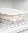 Heavy Duty Clear Plastic Storage Bins With Secure Snap On Lids Super Solid Twelve Quart Capacity Sweet Four Pack holding towels in a cabinet.