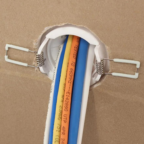 White 2-inch cable pass-through port, pair, installed in drywall with blue and orange cables.
