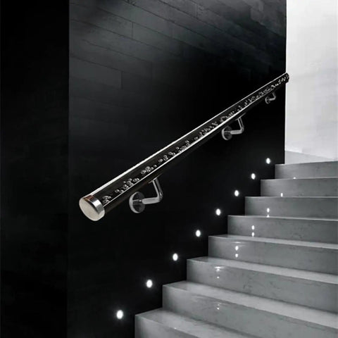 Sleek Transparent Acrylic Handrail With Heavy Duty Silver Wall Mount Brackets For Indoors Outdoors Stair And Deck Safety Featuring Bubble Design Supporting Four Hundred Forty Pounds Built Like A Tank For Daily Grind mounted on sleek black wall beside illuminated stairs.