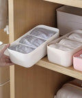 Stackable Plastic Underwear Storage Containers With Divided Compartments To Straighten Up Your Wardrobe Kick Clutter To The Curb Keeping Socks Bras Neck Ties Squeaky Fresh on a wooden shelf.
