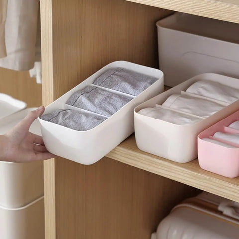 Stackable Plastic Underwear Storage Containers With Divided Compartments To Straighten Up Your Wardrobe Kick Clutter To The Curb Keeping Socks Bras Neck Ties Squeaky Fresh on a wooden shelf.