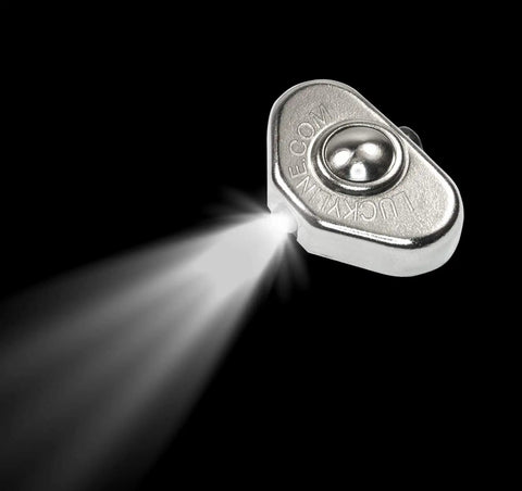 Ultra Compact Stick On LED Thumb Light That Turns Keys, Tools, Cabinets, Leashes And More Into A Bright Flashlight emitting light on black background