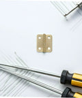 Close-up of a gold hinge from the 40 Pcs Mini Iron Hinge Set With Screws For Jewelry Boxes And Tiny Chests 270 Degree Rotation.